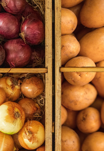 divided box of yellow potatoes, yellow onions and red onions.